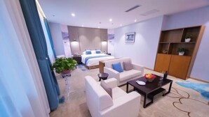 A hotel room with a bed, a sofa, a coffee table, a TV, and a plant. - Yangling International Conference & Exhibition Center Hotel (Xianyang)