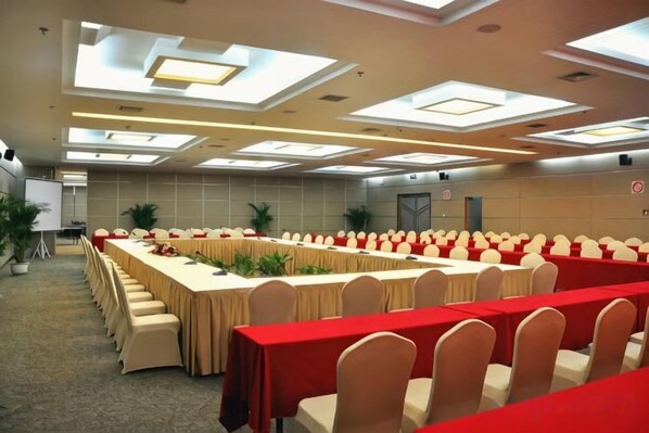 A conference room with long tables and chairs, a whiteboard, and potted plants.