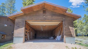 A large wooden building with a covered entrance and a dirt driveway. - Peaceful Cabin Nestled in the Pines with a Short Walk to Lake Granby (Granby)