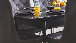 A dining table with black chairs, a fruit bowl, and two glasses of orange juice. - Stunning Wembley Flat | 2 Baths (Greater London)