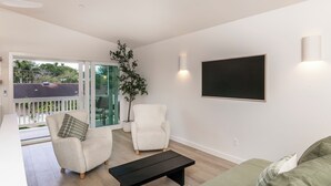 A modern living room with a sofa, armchairs, a coffee table, and a large window with a view of greenery.