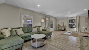 A spacious living room with a green sectional sofa, a round coffee table, and a wooden floor. - Escape to comfort at Be Cozy Getaway! Located in a serene neighborhood in Euclid. (Euclid)