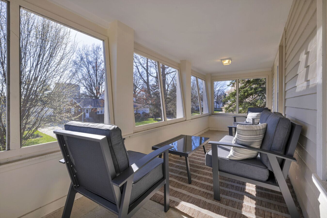 A sunroom with large windows, a glass table, and two chairs.