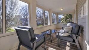 A sunroom with large windows, a glass table, and two chairs. - Escape to comfort at Be Cozy Getaway! Located in a serene neighborhood in Euclid. (Euclid)