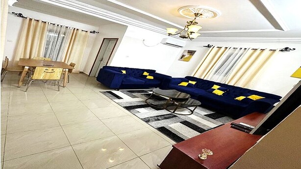A living room with a sofa set, a dining table, and a chandelier. - Luxury furnished studio (Douala)