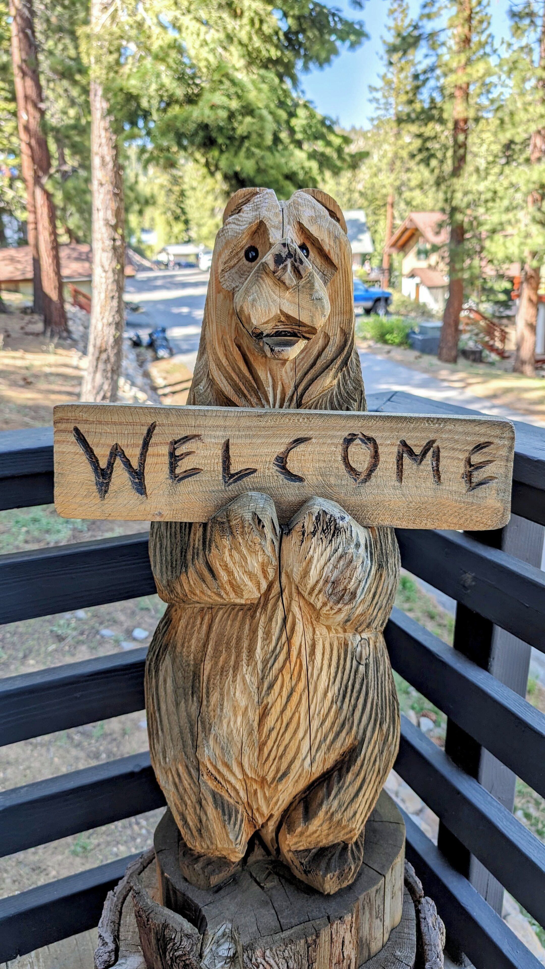 A wooden bear sculpture holding a 'WELCOME' sign.