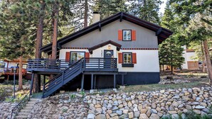 A two-story lodge with a stone foundation, a balcony with a railing, and a chimney.