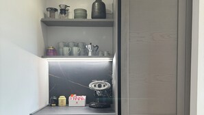 Eine kompakte Küche mit integrierter Kaffeemaschine, einem Regal für Küchenutensilien und einer kleinen Arbeitsfläche.