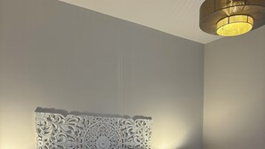Ein ordentlich bezogenes Bett mit einem gemusterten Kopfteil, zwei Nachttischlampen und einem Teppich mit Struktur.