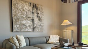 Ein modernes Wohnzimmer mit einem grauen Ecksofa, einem runden Couchtisch und einem großen abstrakten Gemälde an der Wand.