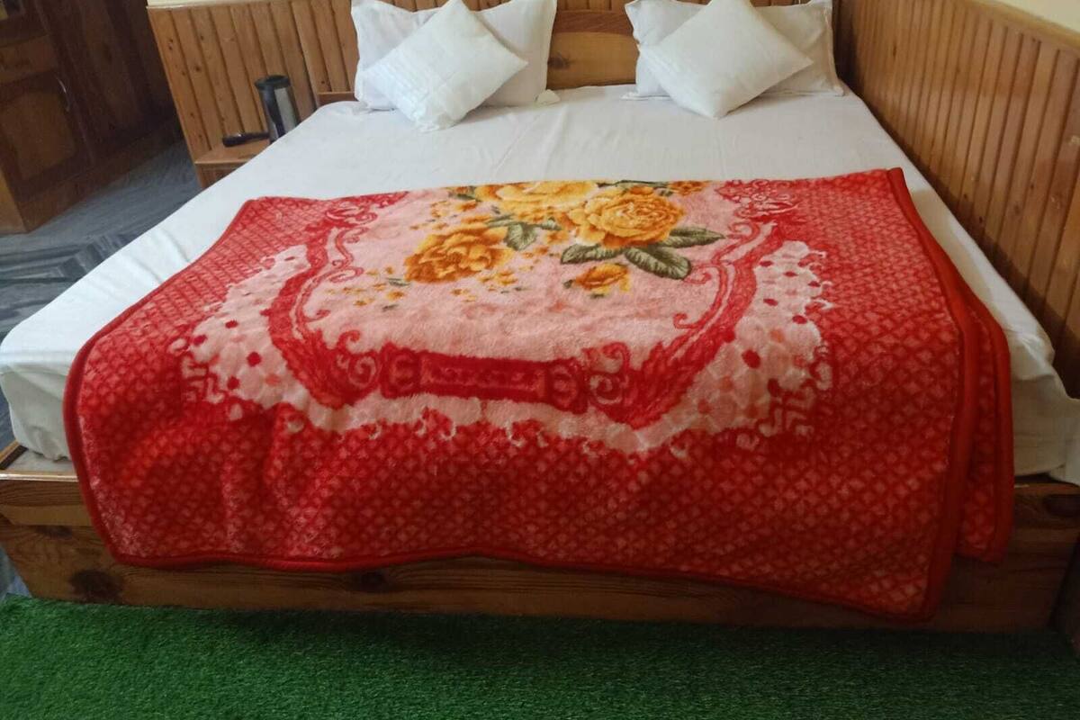 A bed with a floral-patterned blanket, white pillows, and a wooden headboard.