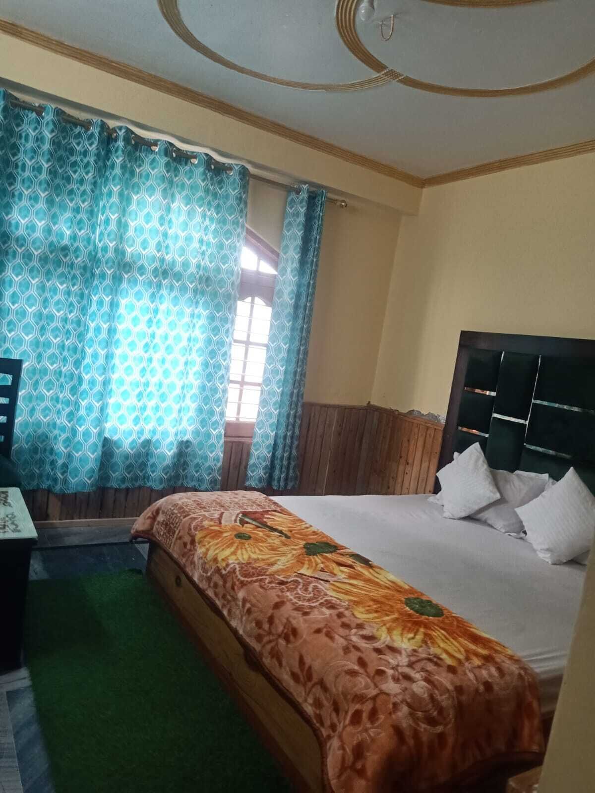 Una habitación de hotel con cama, escritorio y ventana con cortinas.