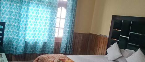 Una habitación de hotel con cama, escritorio y ventana con cortinas.