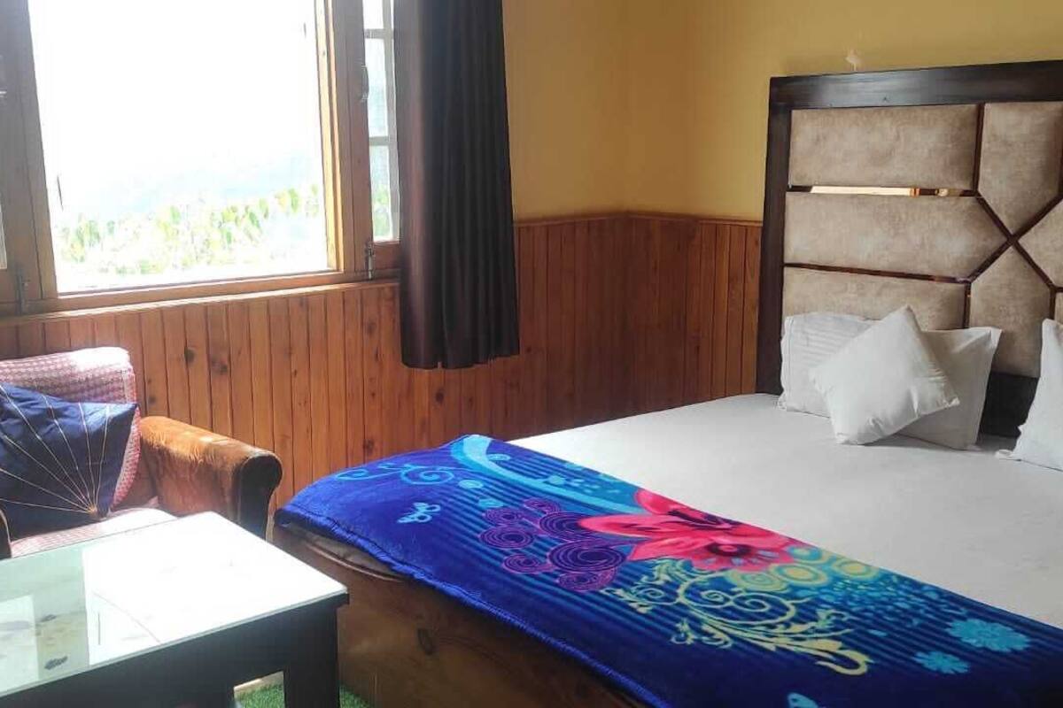 A room with a bed, a chair, a table, and a window with curtains.