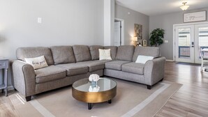 A modern living room with a grey sectional sofa, a round coffee table, and a minimalist decor.