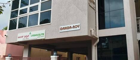 Un edificio de varios pisos con un letrero que dice 'Ganga-Roy Urban Elite Apartment Hotel' y una motocicleta estacionada.