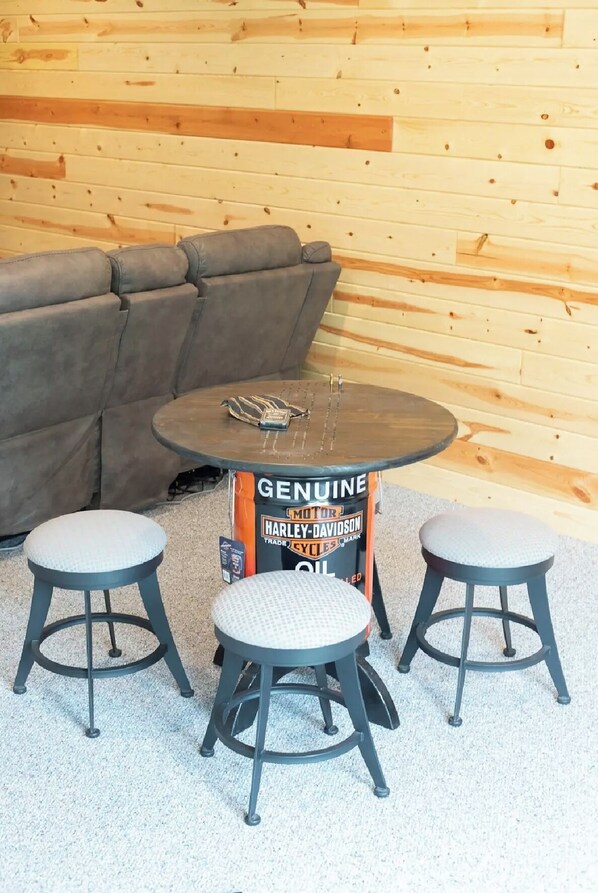 A seating area with a round table and two stools, a brown leather couch, and a wooden wall. - Serene Lakefront Escape with stunning views-ATV Trails & Golf all within a mile. (Rice Lake)