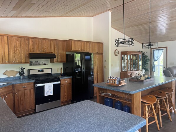 A modern kitchen with wooden cabinets, a stainless steel refrigerator, and a granite countertop.