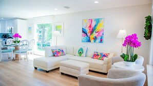 A modern living room with a sectional sofa, a dining area with a table and chairs, and a kitchen in the background. - Family Tides (Destin)