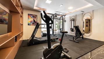 Un gimnasio con equipo de ejercicio, una cinta de correr y un espejo.