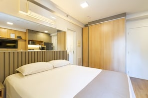 A modern hotel room with a bed, a TV, a kitchenette, and a wardrobe. - Studio p. Allianz e Hosp Albert Einstein (São Paulo)
