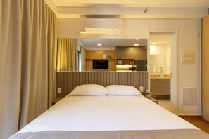 Una camera d'albergo con un letto, una televisione, angolo cottura e bagno.