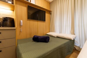 A room with a bed, a television mounted on the wall, a telephone, and a window with curtains. - Studio p. Allianz e Hosp Albert Einstein (São Paulo)