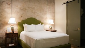 Una cama bien hecha con sábanas y almohadas blancas, flanqueada por dos mesitas de noche con lámparas.