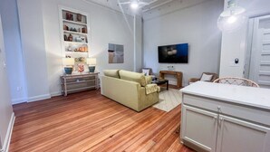 A living room with a sofa, a TV, a bookshelf, and a cabinet. - Cane - The Flats Demopolis (Demopolis)