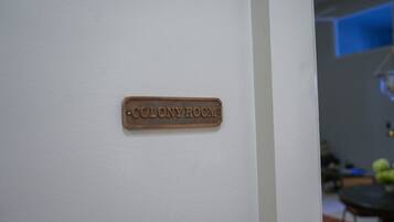 Una señal en una pared blanca que dice 'COLONY ROOM'.