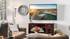 A modern living room with a flat-screen TV mounted on the wall, a sofa, a coffee table, and a decorative plate. - Old Town Pool Home: Patio Bar (Scottsdale)