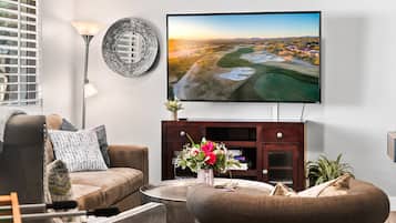 Un soggiorno moderno con una TV a schermo piatto montata a parete, un divano, un tavolino da caffè e un piatto decorativo.