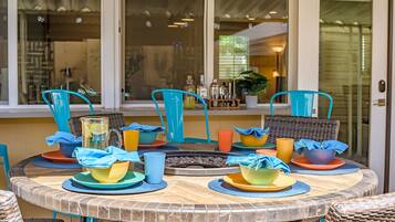 A round table with colorful plates and cups, blue chairs, and a wicker basket.