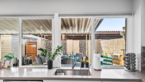 A modern kitchen with a large window, stainless steel appliances, and a potted plant. - Old Town Pool Home: Patio Bar (Scottsdale)