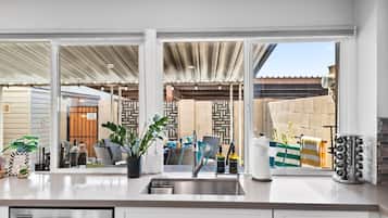 A modern kitchen with a large window, stainless steel appliances, and a potted plant.