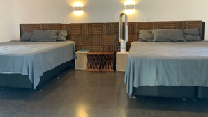 A hotel room with two beds, a wooden headboard, a small table, and a wall-mounted air purifier.
