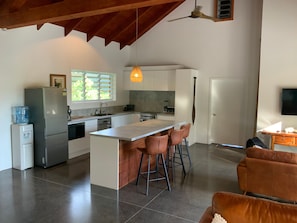 Uma cozinha moderna com uma ilha central, banquetas, geladeira e dispensador de água.