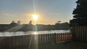 Un atardecer sobre una masa de agua con una valla de madera en primer plano.