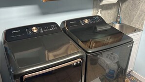 Una lavandería con dos lavadoras Samsung y un lavamanos.