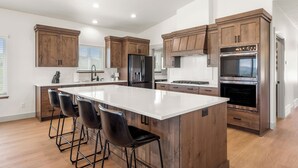 A modern kitchen with wooden cabinets, stainless steel appliances, and a large island with bar stools.