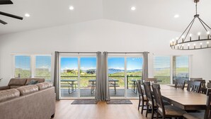A spacious living room with a large sliding glass door leading to a balcony with a scenic view.