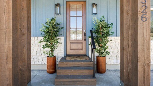A wooden staircase leading to a door with two potted plants on either side.