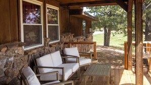 Eine hölzerne Veranda mit Steinmauern, einer gepolsterten Couch und einem kleinen Tisch.