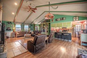 Een ruime woonkamer met leren banken, een eethoek en een keuken met groene kastjes.