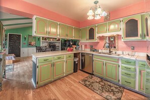 A kitchen with green cabinets, a wooden floor, and a chandelier.