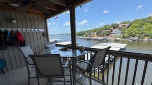Un balcón con mesa y sillas con vista a un río donde se ven barcos y casas al fondo.