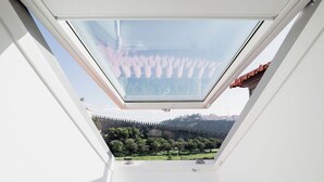 A skylight with a view of a green landscape and a distant building. - Porto D'Alma - Infante D.Henrique - T1 (Porto)