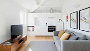 A modern living room with a grey sofa, wooden entertainment unit, and a flat-screen TV. - Porto D'Alma - Infante D.Henrique - T1 (Porto)