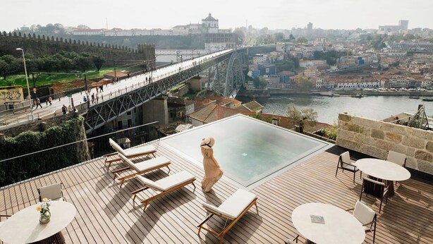 A rooftop terrace with a glass infinity pool, lounge chairs, and a view of a cityscape including a bridge. - Porto D'Alma - Infante D.Henrique - T1 (Porto)
