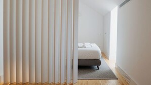 A modern bedroom with a bed, a wooden floor, and a white wall. - Porto D'Alma - Infante D.Henrique - T1 (Porto)